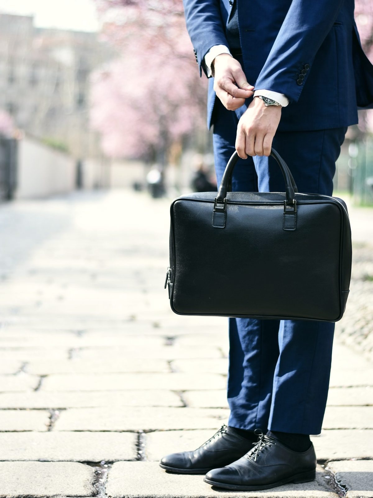 A man in a navy suit carrying a black leather briefcase