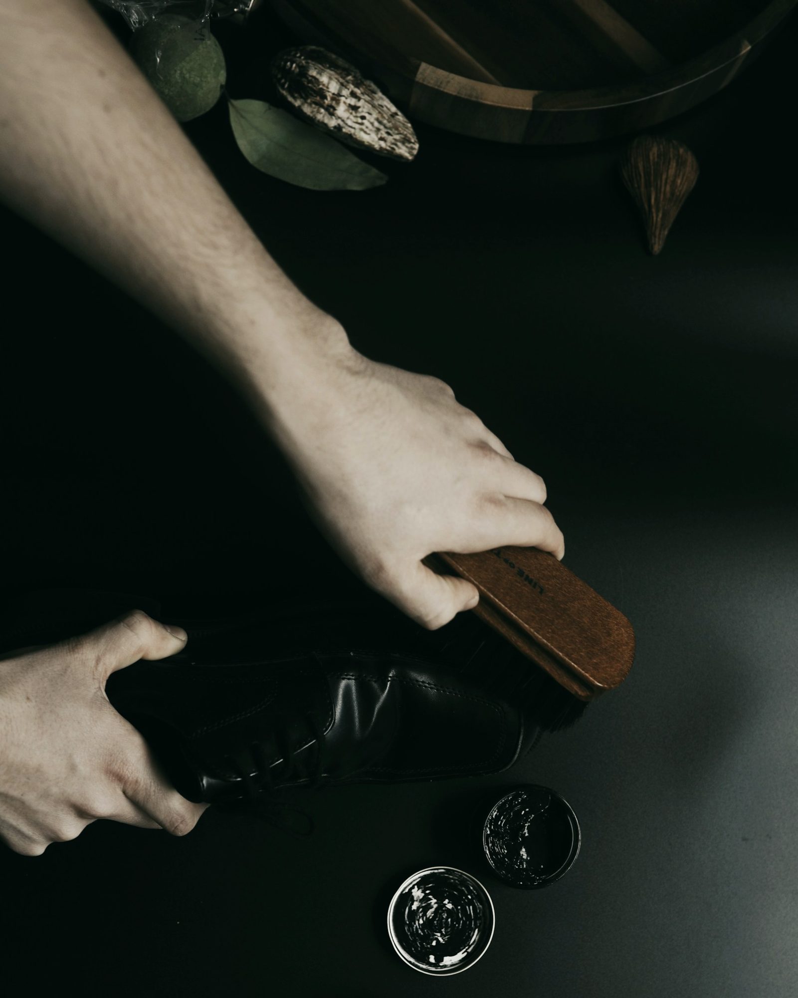 Hand-polishing a dark leather shoe with a brush and wax