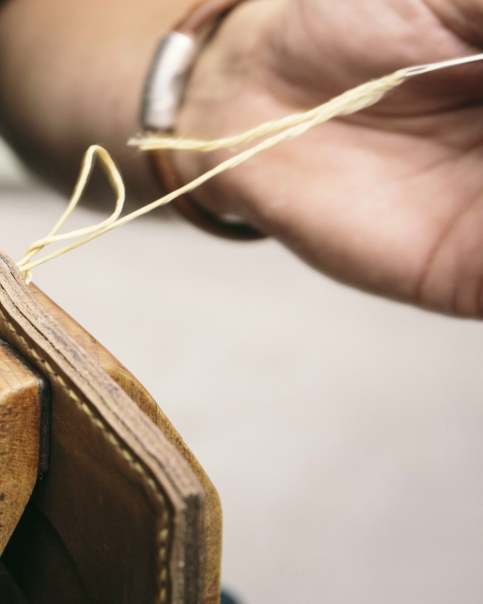 Hand saddle-stitching with waxed thread at a stitching clam