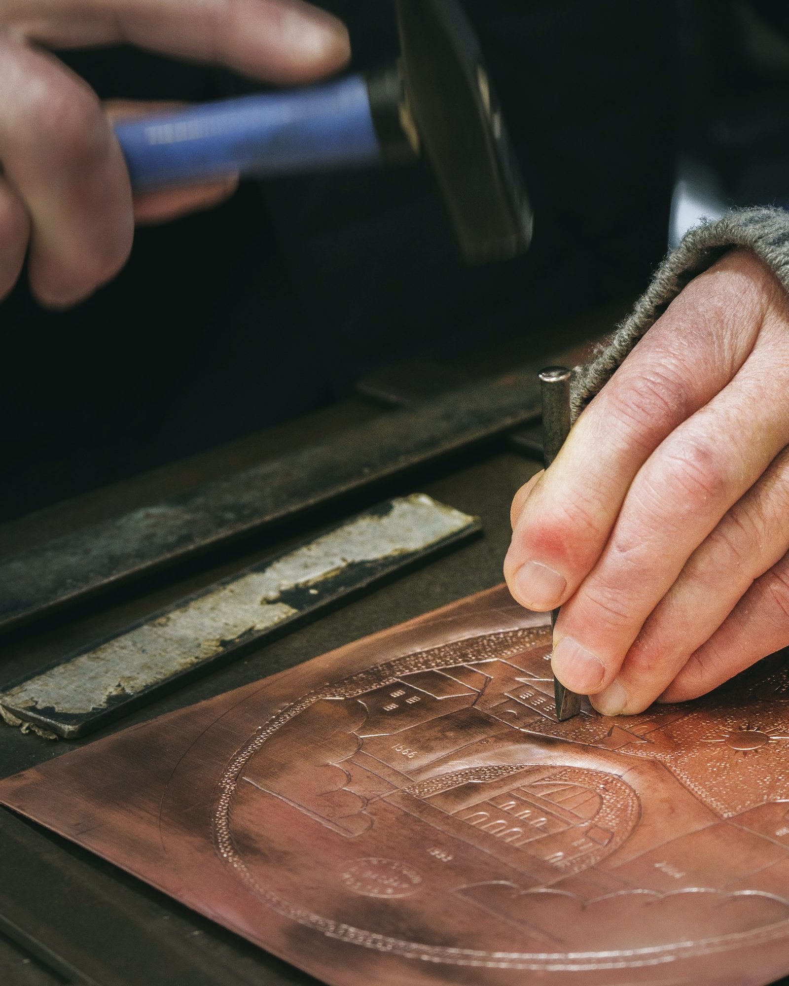 A craftsman stamping a design into leather with a mallet