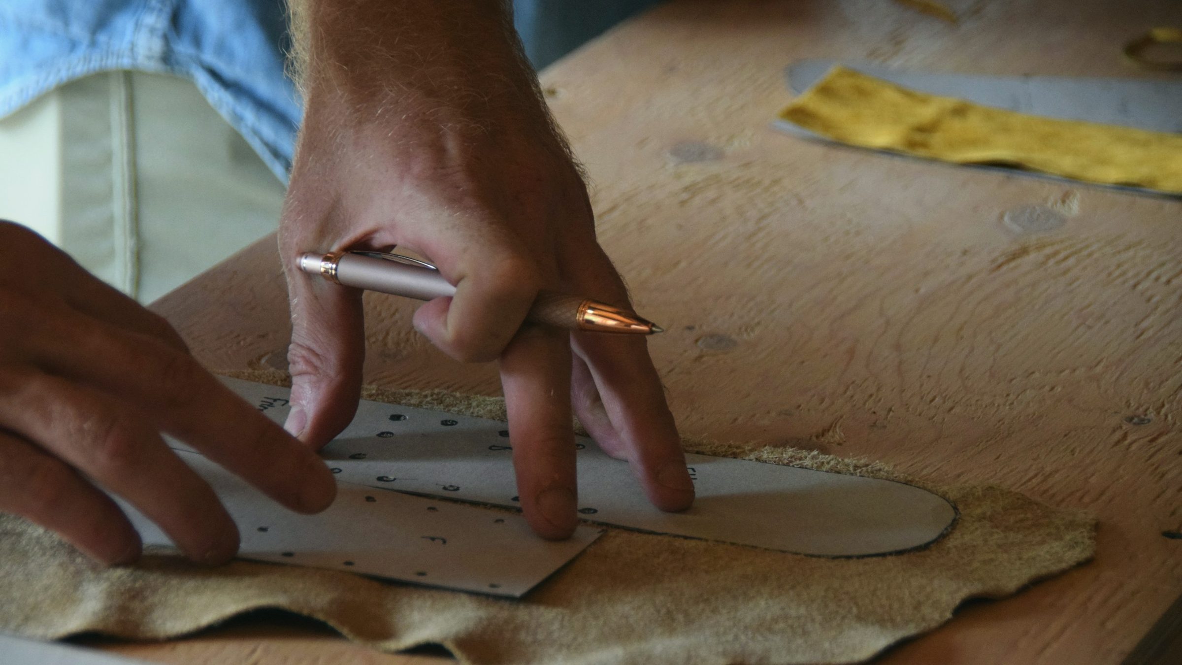 An artisan's hands marking a pattern onto a hide before cutting